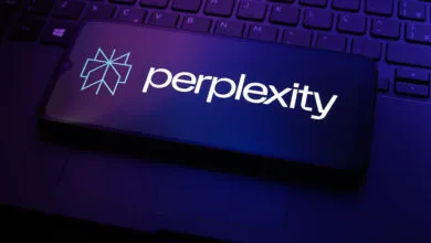Smartphone displays Perplexity AI logo on laptop keyboard, dark blue lighting.