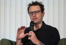 Nathan Fielder speaking into a microphone with hand gestures.