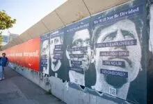 Mural showing AI surveillance protest with portraits of tech leaders.