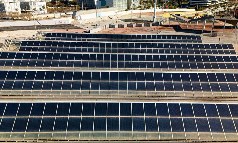 Aerial view of solar panels on a rooftop, city buildings in background.