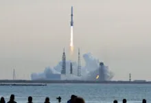 Rocket launches from Cape Canaveral, plume of smoke and fire visible.