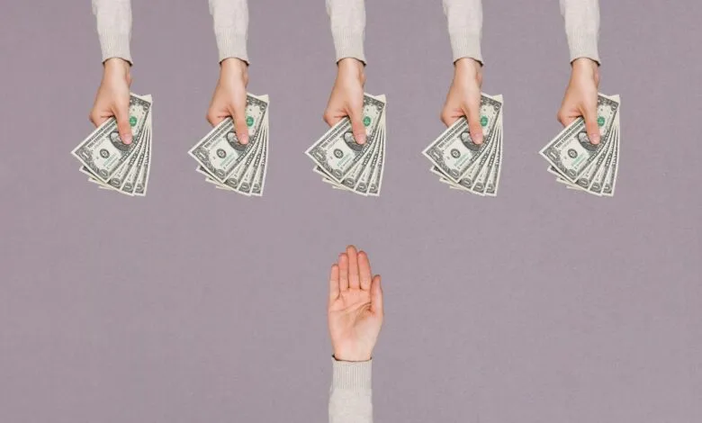 Five hands offer money to a raised hand on gray background.