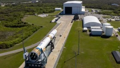 Blue Origin rocket on transporter moving towards launch facility.