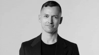 Black and white portrait of a man in a blazer smiling slightly.