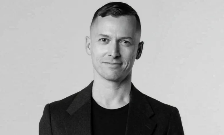 Black and white portrait of a man in a blazer smiling slightly.