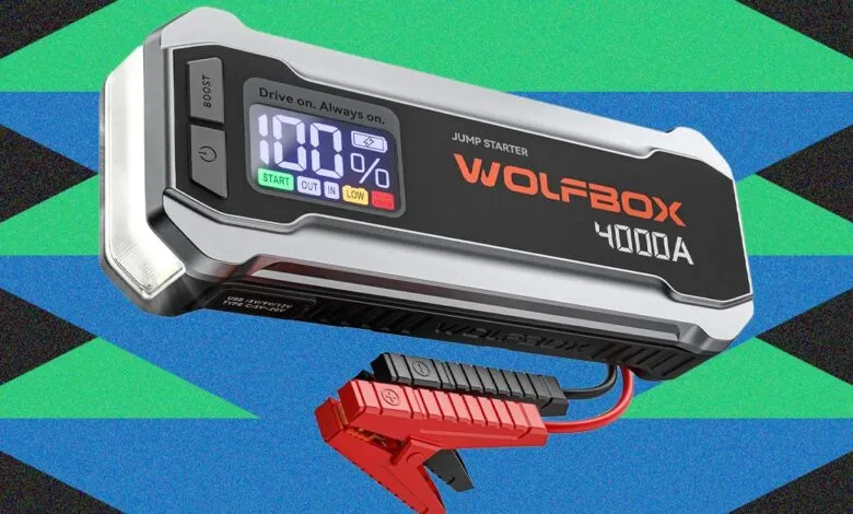 Wolfbox 4000A jump starter with clamps, display showing 100% charge.