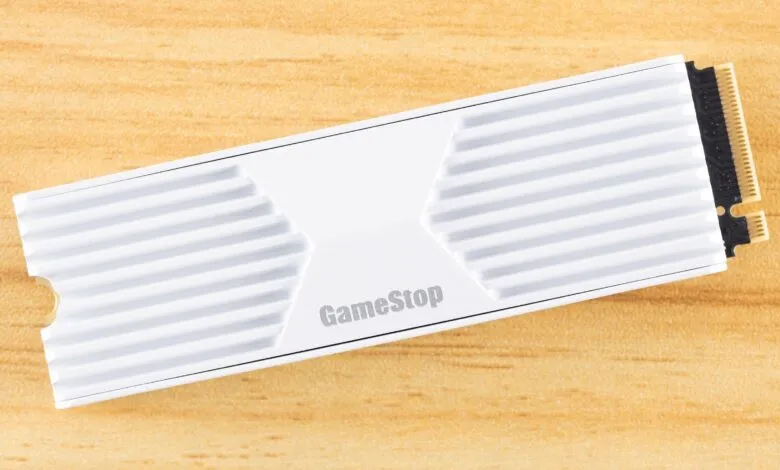 GameStop branded NVMe SSD with white heatsink on wood surface.