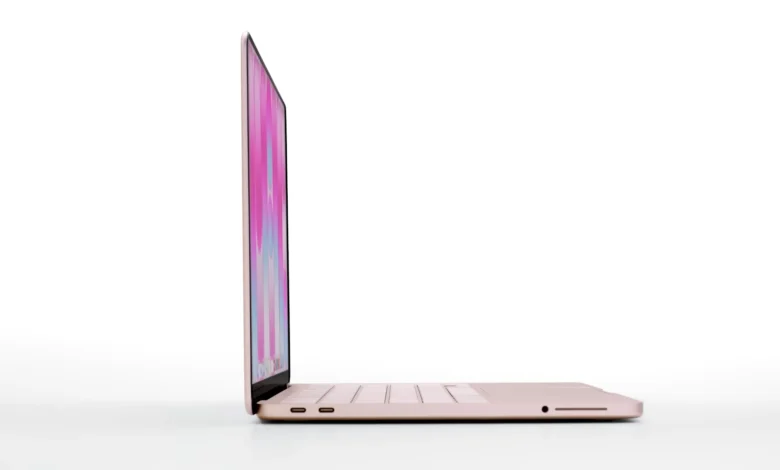 Side view of a rose gold laptop with a colorful screen on a white background.