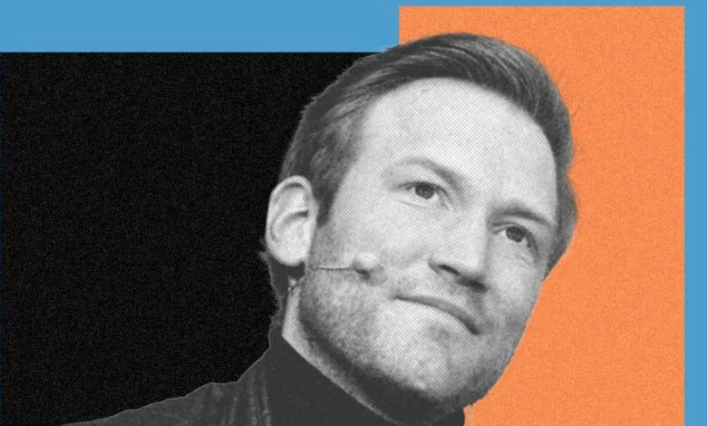 Headshot of a man with a microphone against a colorful, geometric background.