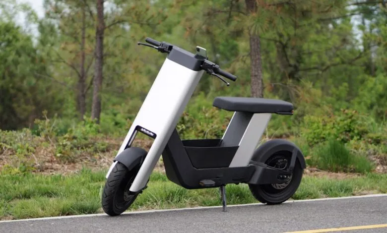 Modern white and black electric scooter parked on asphalt road.