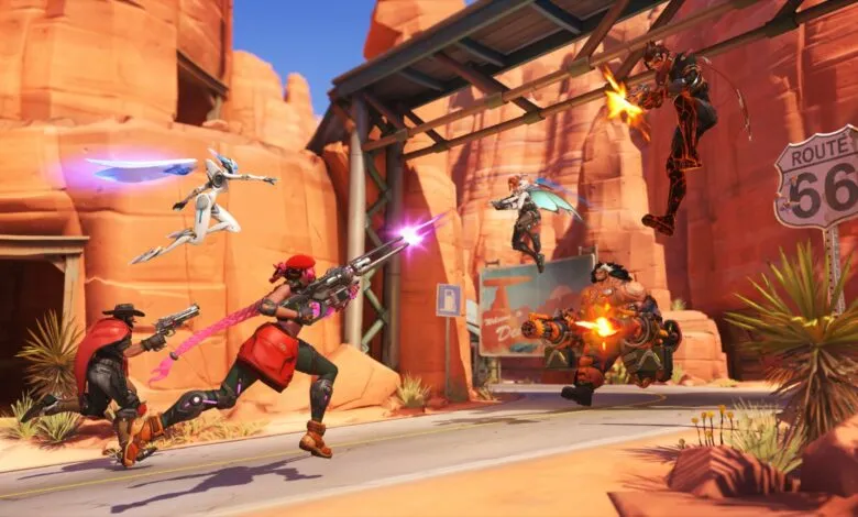 Overwatch 2 characters in a desert battle scene with Route 66 sign.