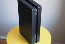 Black PlayStation 5 console standing vertically on a yellow table.