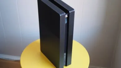 Black PlayStation 5 console standing vertically on a yellow table.