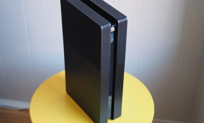 Black PlayStation 5 console standing vertically on a yellow table.