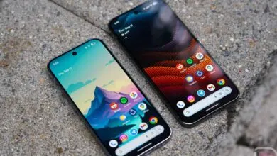 Two smartphones displaying home screens with app icons on a textured gray surface.