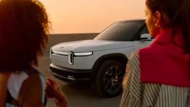Rivian R2 electric SUV in Glacier White with two people in foreground.