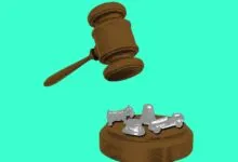 Gavel poised above Monopoly game pieces on a wooden block.
