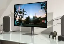 Gaming setup featuring Cyberpunk 2077 on a monitor with speakers and decorative items.