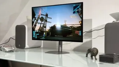 Gaming setup featuring Cyberpunk 2077 on a monitor with speakers and decorative items.