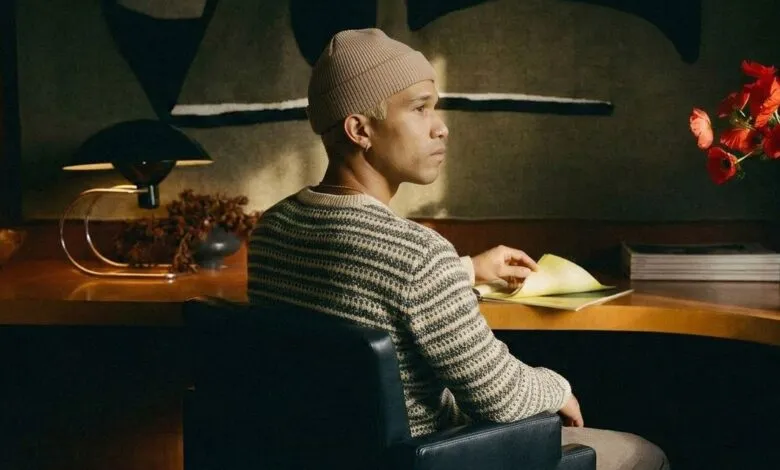 Person with beanie sitting at desk with papers and flowers.