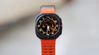 Close-up of a smartwatch with an orange band and a complex watch face.