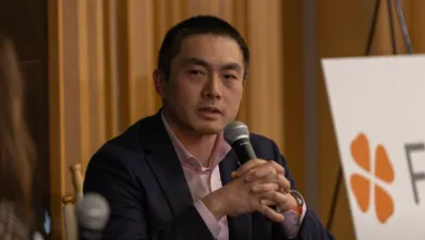 Eric Yuan, Zoom CEO, speaks at a conference, holding a microphone.