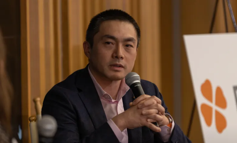 Eric Yuan, Zoom CEO, speaks at a conference, holding a microphone.