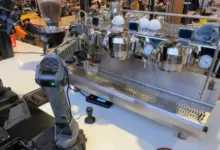 Robotic arm making espresso with a professional machine.