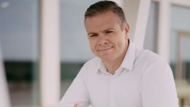 Portrait of a man in a white shirt smiling slightly at the camera.