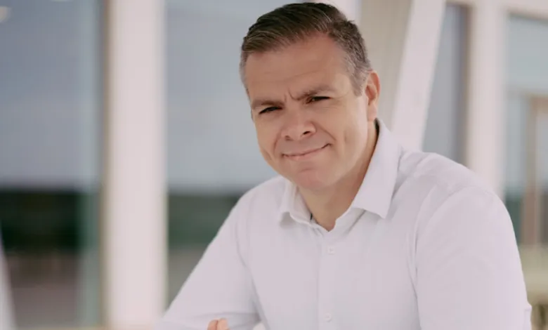 Portrait of a man in a white shirt smiling slightly at the camera.