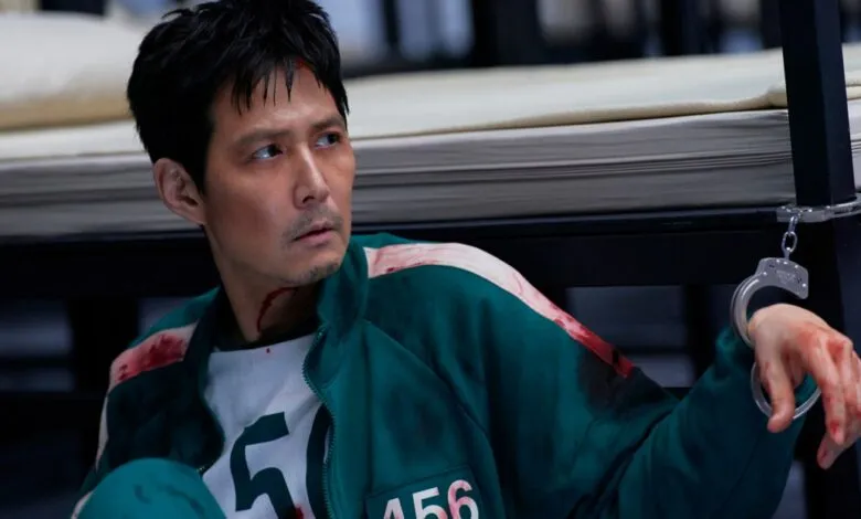 Lee Jung-jae as Seong Gi-hun in Squid Game, looking distressed with blood and handcuffs.