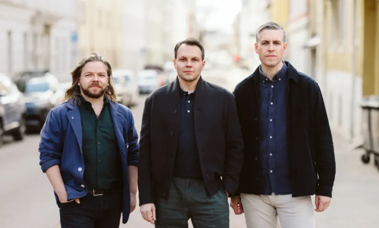Three men stand side-by-side on a city street, looking directly at the camera.