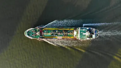 Aerial view of a large oil tanker moving through dark water.