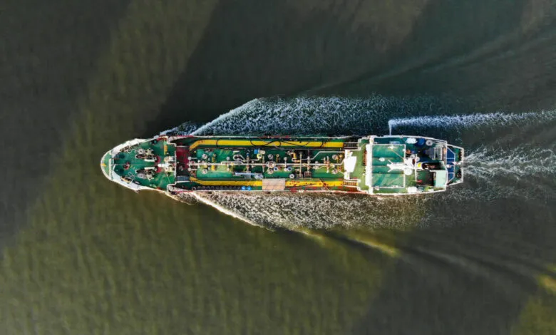 Aerial view of a large oil tanker moving through dark water.