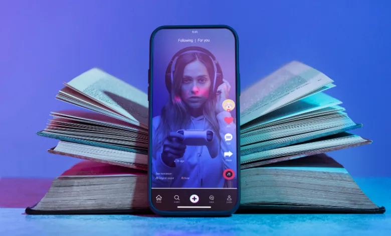 Smartphone displaying TikTok video rests on open books, blue and pink lighting.