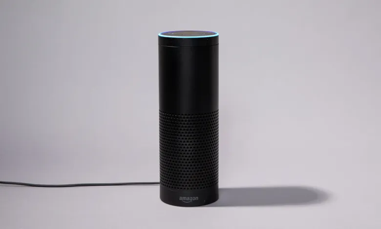 Black Amazon Echo smart speaker with blue light ring on gray background.