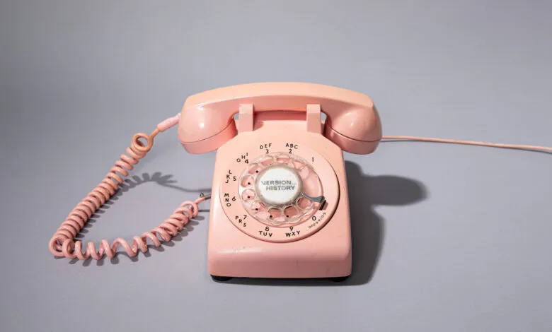 Vintage pink rotary phone with 'Version History' on the dial.