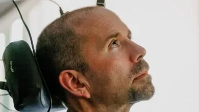 Man in wheelchair with assistive head-mounted technology looks upward.