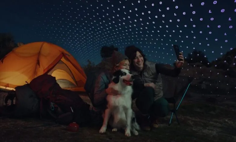 Two women and a dog take a selfie while camping at night.