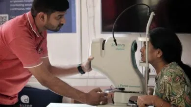 Woman getting eye exam with retinal imaging machine by technician.