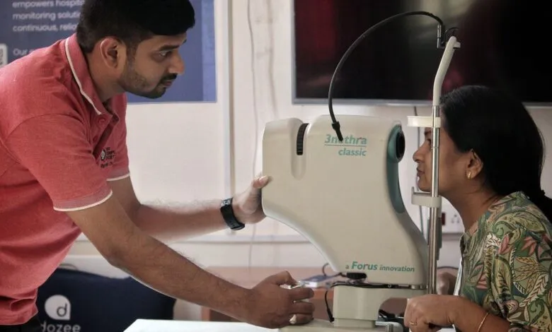 Woman getting eye exam with retinal imaging machine by technician.