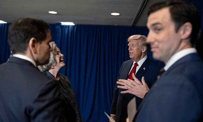 Donald Trump speaks to laughing woman surrounded by men in suits.
