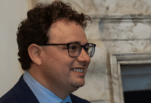 Portrait of a smiling man with curly hair and glasses.