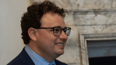 Portrait of a smiling man with curly hair and glasses.