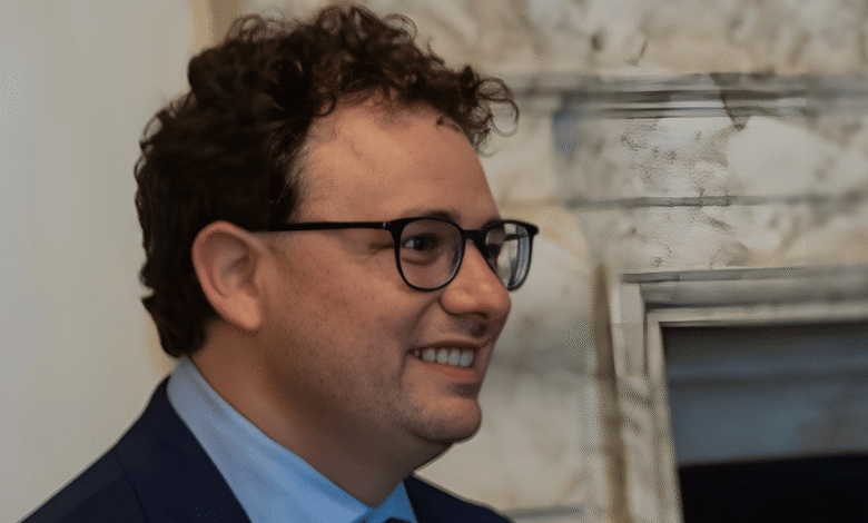 Portrait of a smiling man with curly hair and glasses.