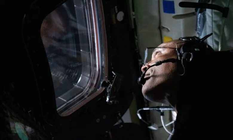 Victor Glover looks out spacecraft window, wearing headset.