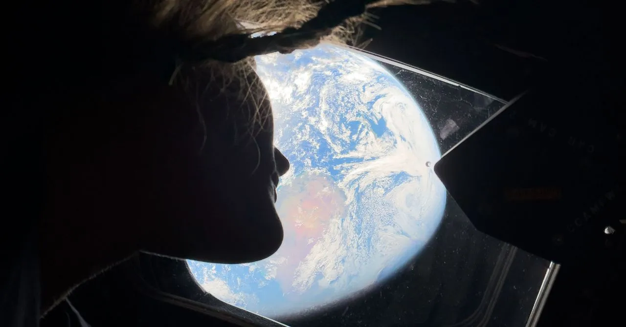 Silhouette of person looking at Earth through a spacecraft window.