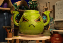 Animated green pot with angry face in a pottery studio setting.