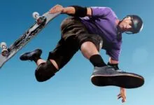 Skateboarder in mid-air performing trick against a clear blue sky.