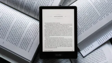 Kindle e-reader displaying 'The Circus Arrives Without Warning' surrounded by books.